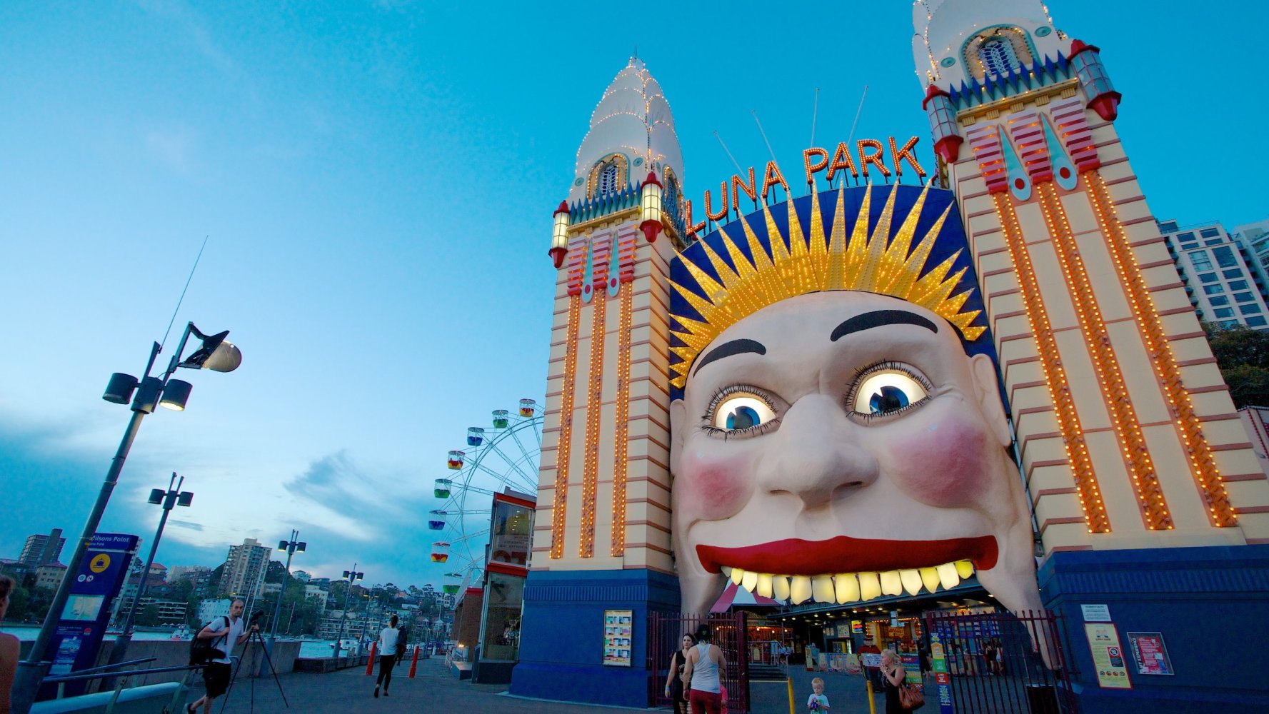 a close up of a person with Luna Park Sydney in the background