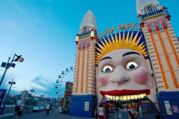a close up of a person with Luna Park Sydney in the background