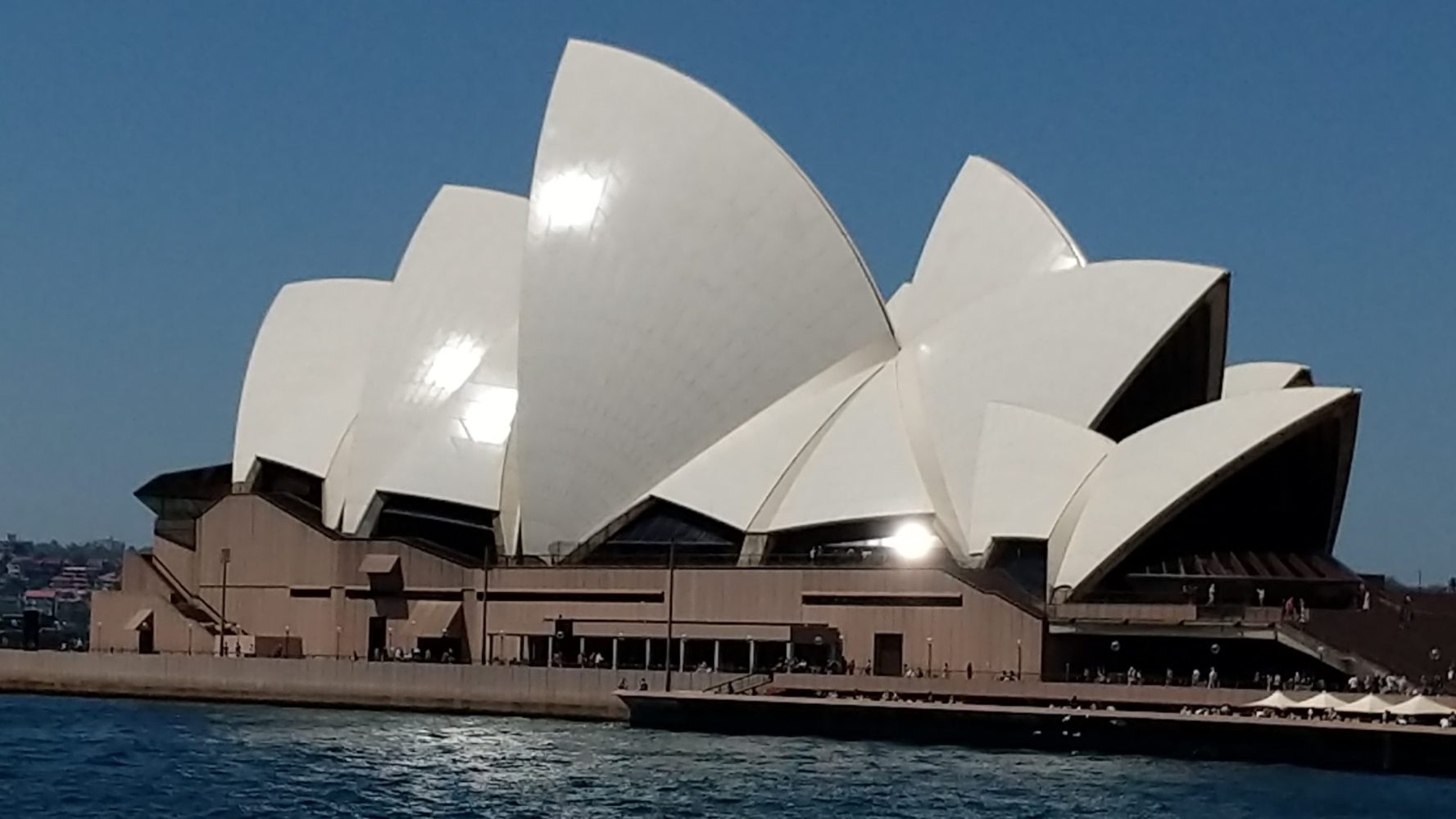 a large ship in the water with Sydney Opera House in the background