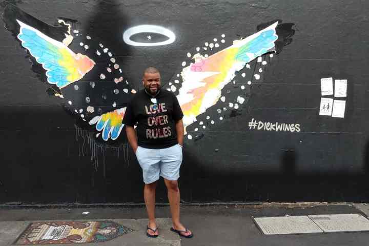 Juan Carlos Gómez holding a kite while standing on a sidewalk