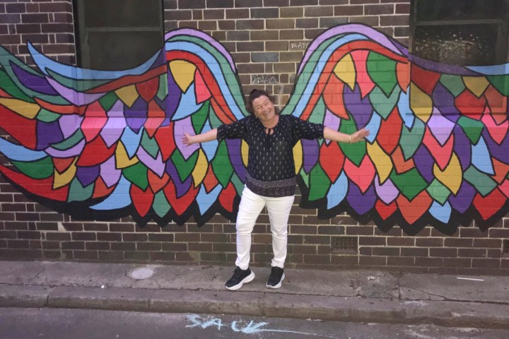 a person standing in front of a graffiti covered wall