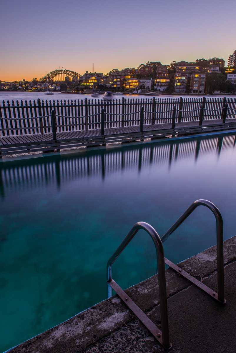 a bench near a metal rail next to a body of water