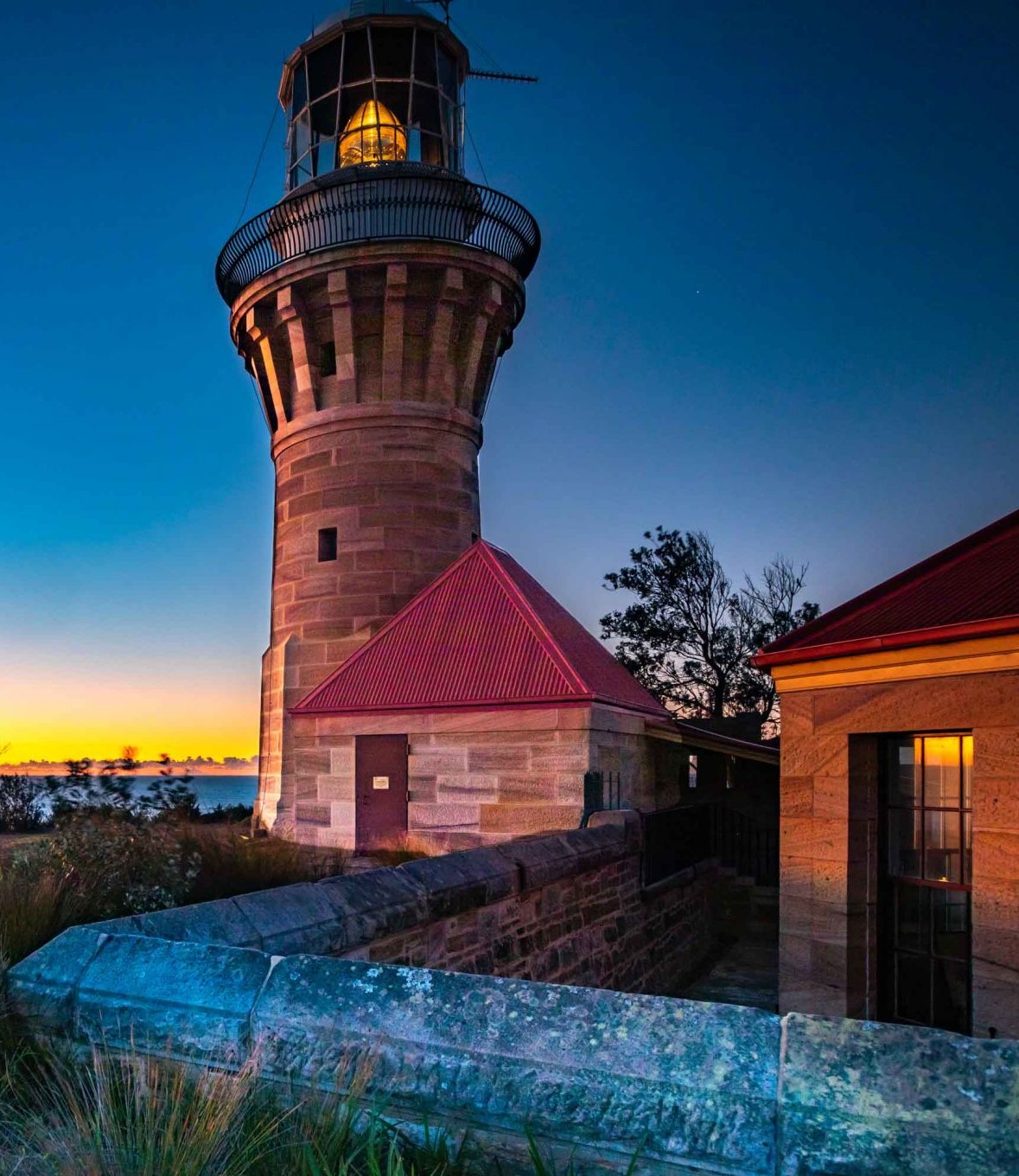 barrenjoey-lighthouse-sunrise-palm-beach-sydney-australia_l a large brick building with a tower in the background